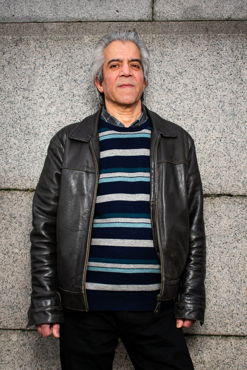 Portrait of Almas, wearing a leather jacket with striped shirt underneath.