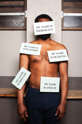 Portrait of Refugee Ohjay hiding his identity with written messages