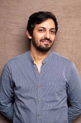 Portrait of refugee Mohammed Swileh wearing a blue shirt smiling.