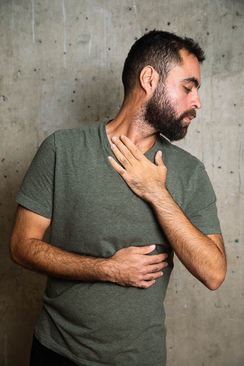 Portrait of refugee Mostafa with his arms hugging his body