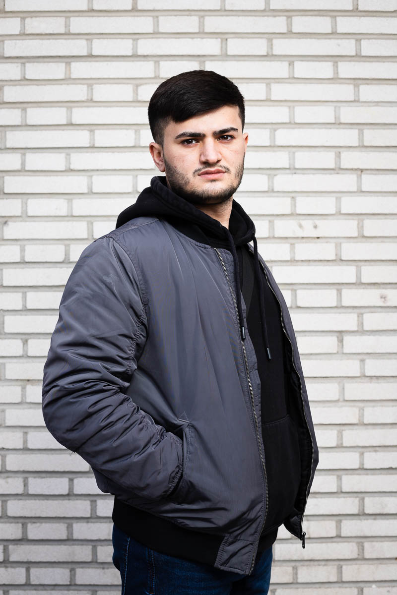 Portrait of refugee Niyaz standing sideways with hands in the jacket's pocket.