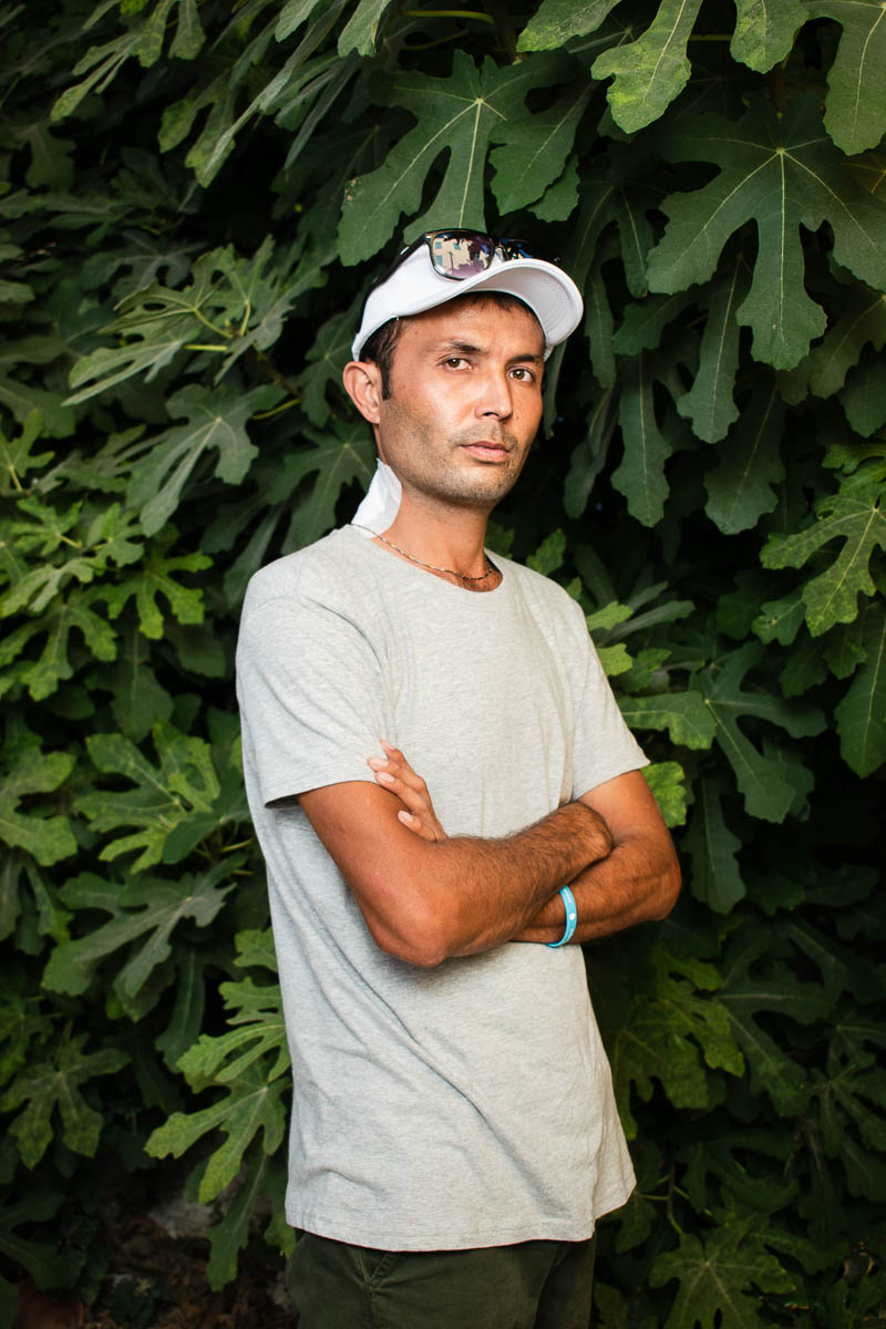 Portrait of refugee Mustafa with a lush green plants backdrop