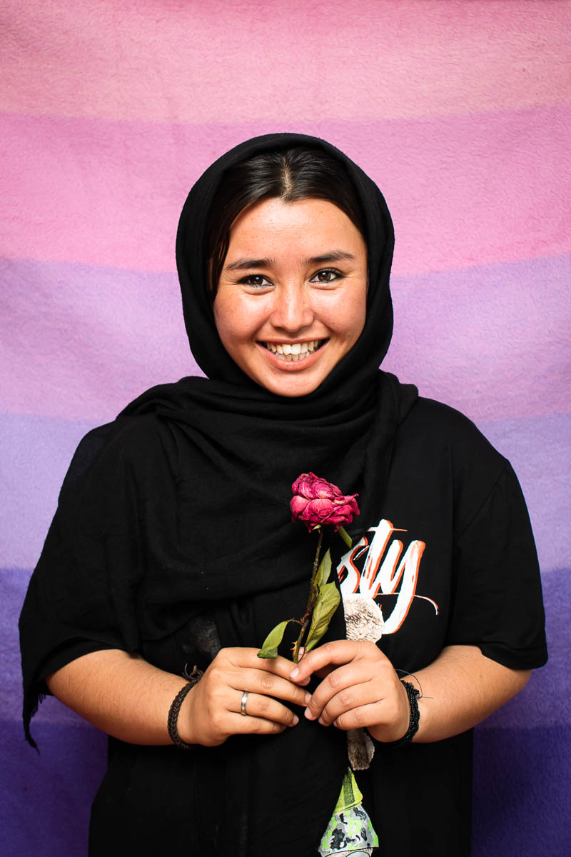 Portrait of refugee Fatemeh holding a rose and smiling