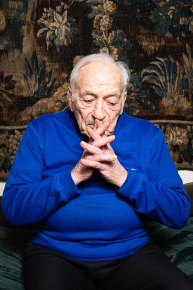 Portrait of former refugee Miguel sitting with his hands folded