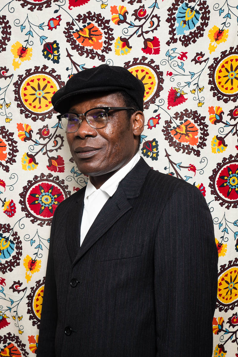 Portrait of refugee Pat in a beret against a colorful background