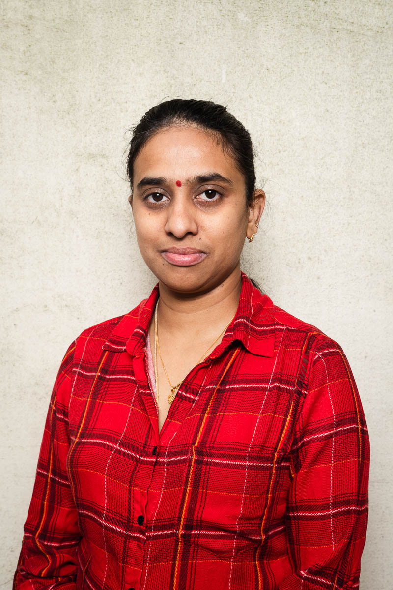 Portrait of refugee Nitha wearing a red plaid shirt