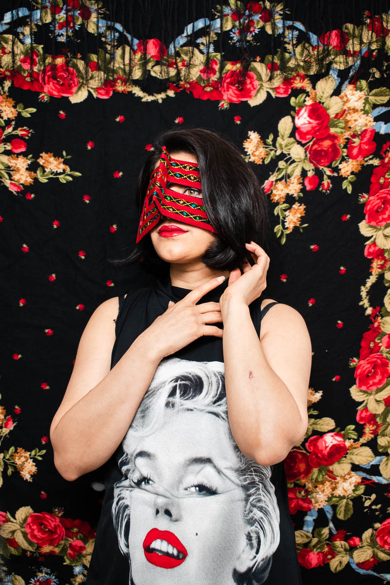 Portrait of refugee Azadeh wearing a red mask against a floral background
