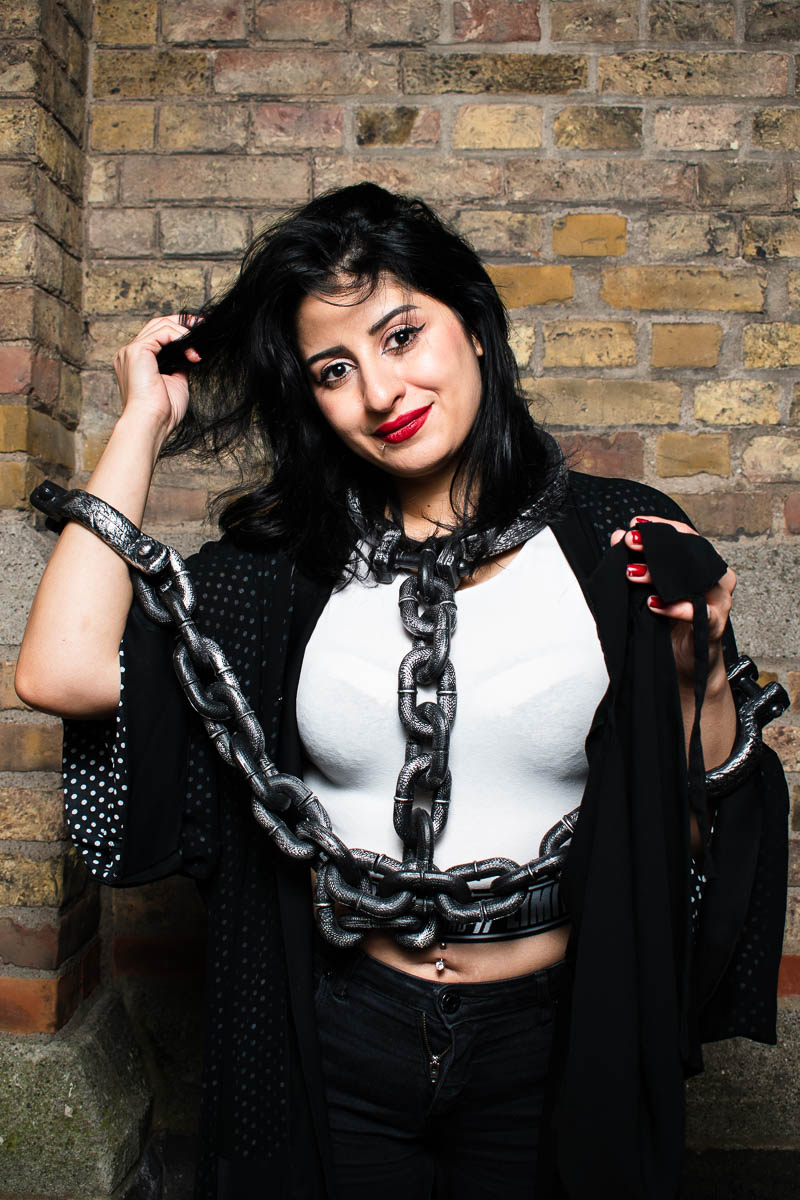 Portrait of refugee Rana wearing a prop that looks like chains bound to her hands and neck