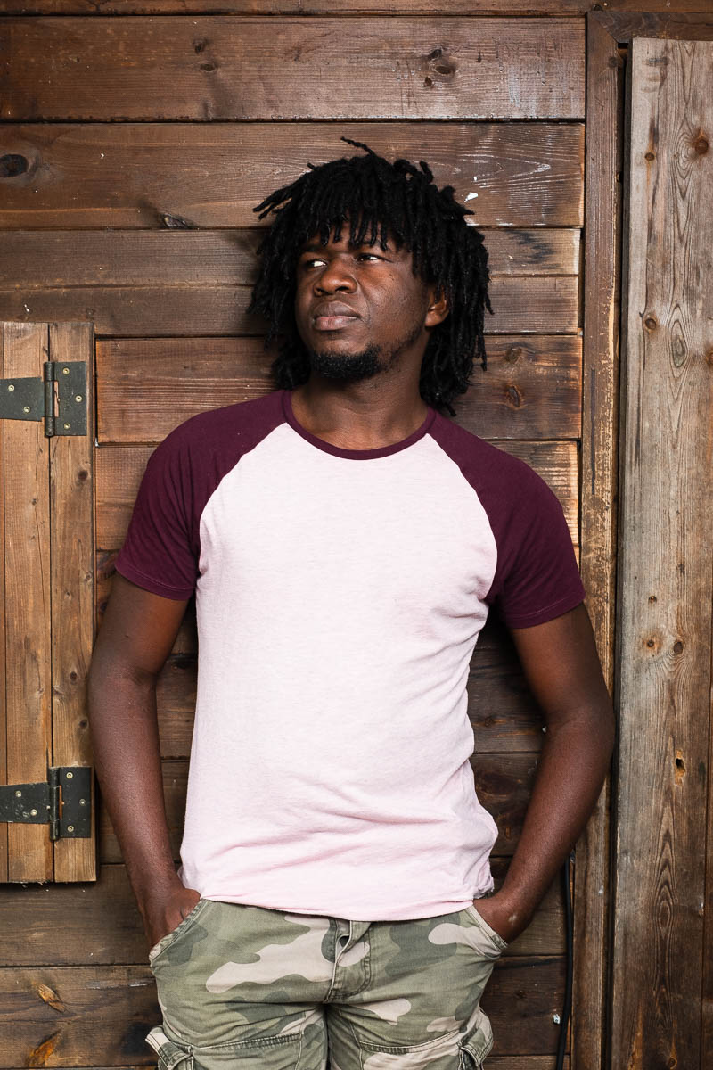 Portrait of refugee David against a wooden door