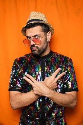 Portrait of refugee Le Petit Prince wearing a colorful shirt and holding two hands as peace signs