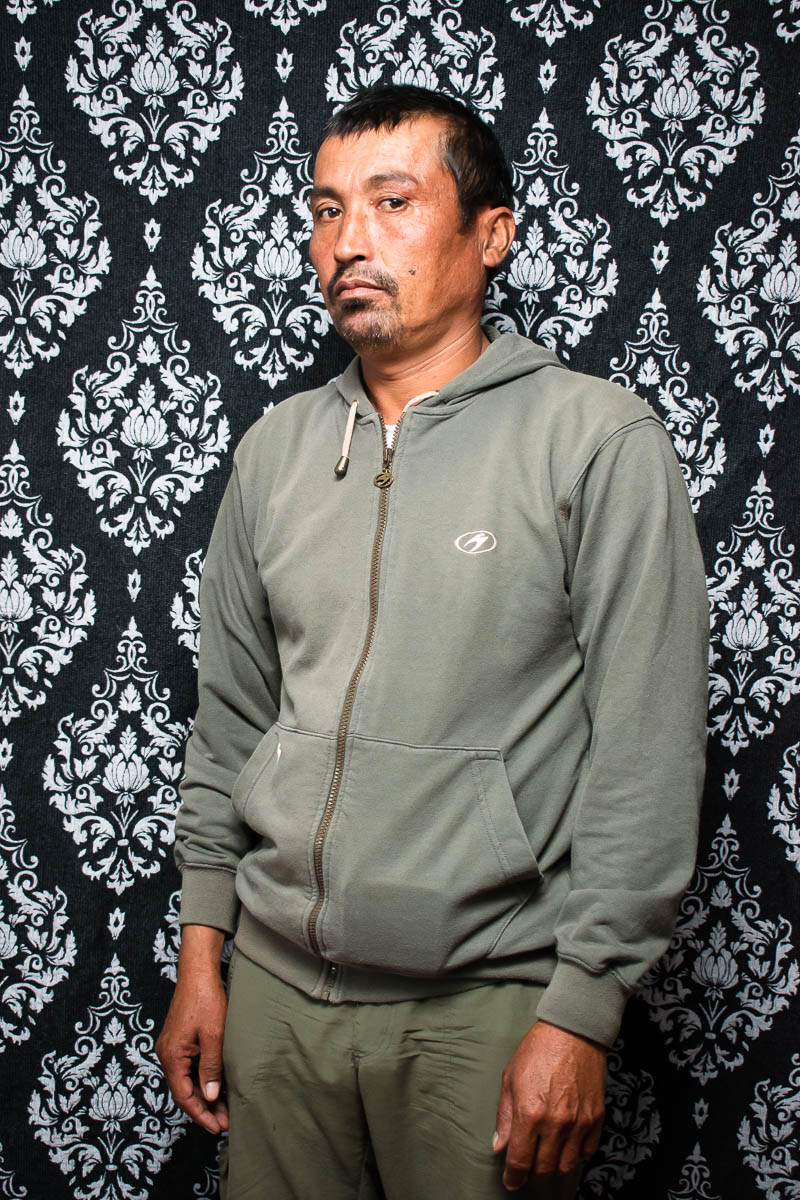 A portrait of refugee Abdull against a black and white patterned background