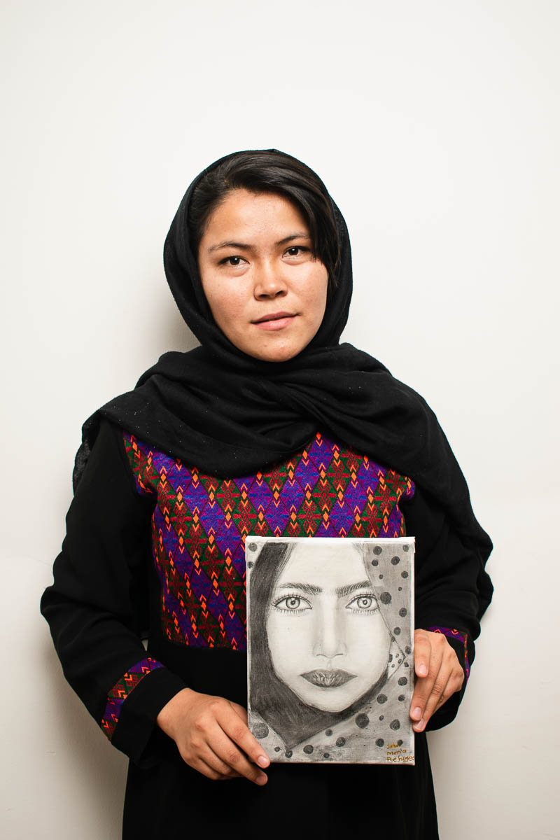 Portrait of refugee Sahar holding a picture she drew