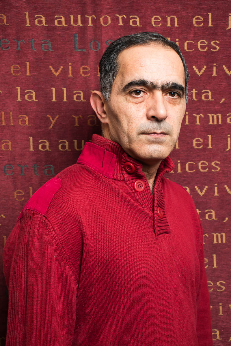 Portrait of refugee Engin wearing a red shirt