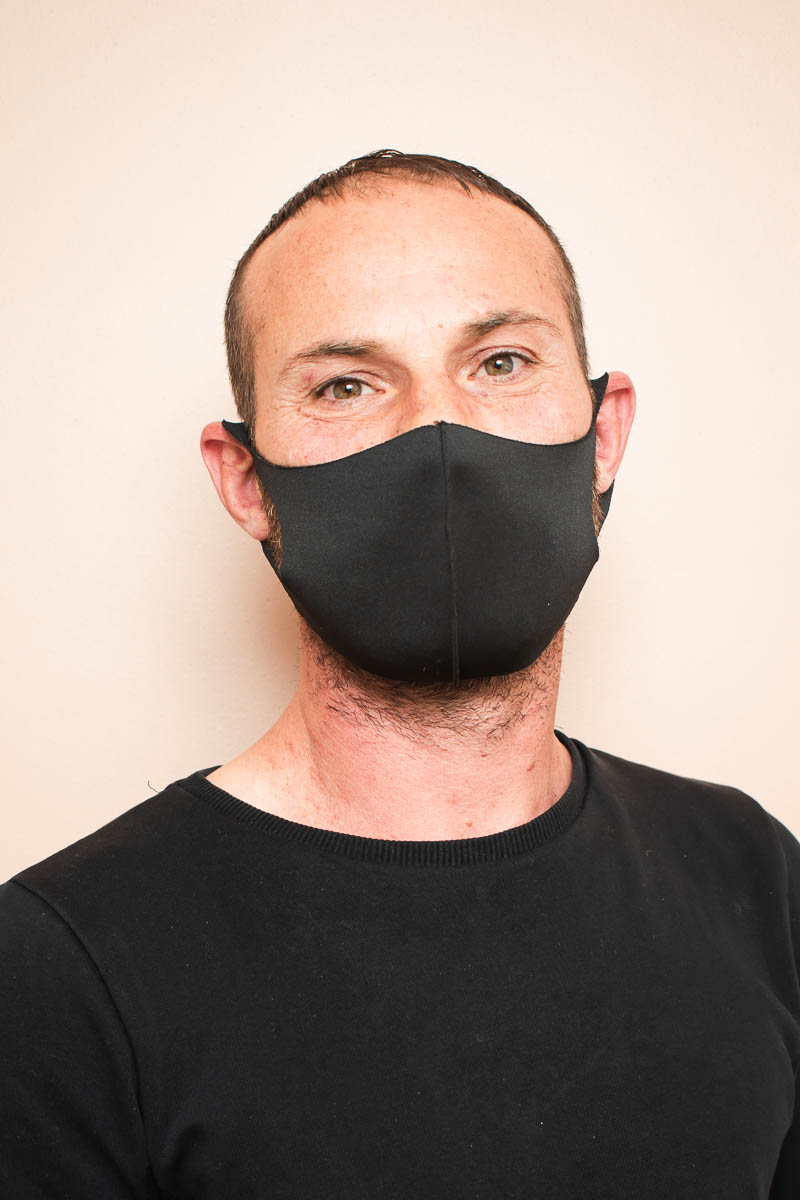 Portrait of refugee Azad wearing a black face mask