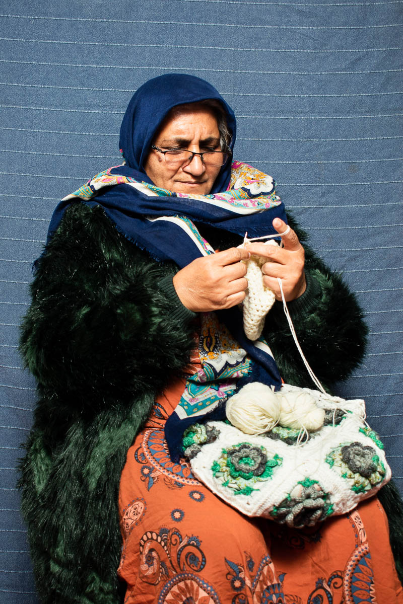 Portrait of refugee Reyhane knitting a woollen shawl