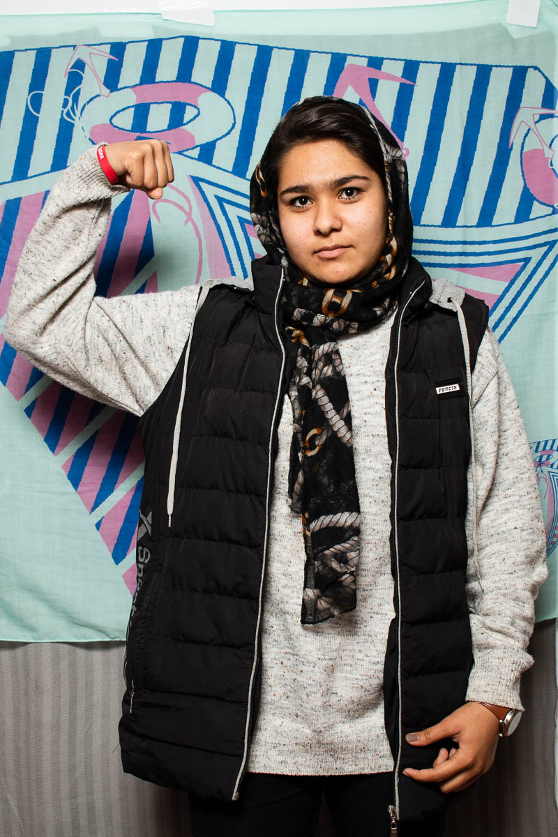 Portrait of refugee Arezo holding her fist in the air