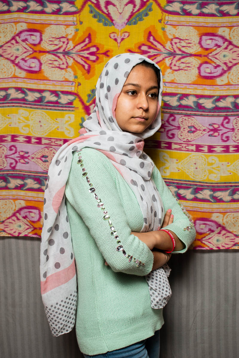 Portrait of refugee Sara with a patterned scarf against a patterned background