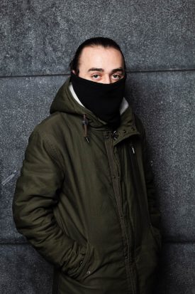 Portrait of refugee Dan wearing a hoodie and a mask covering his face