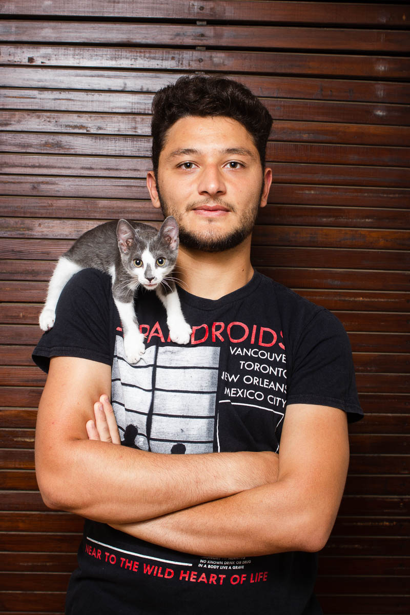 Portrait of refugee Yuosef with a kitten on his shoulder