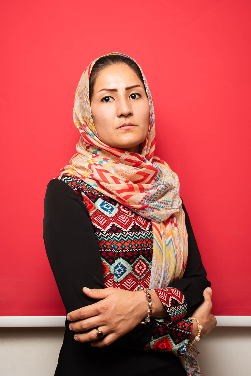 Portrait of refugee Leyla wearing a printed hijab with her hands folded