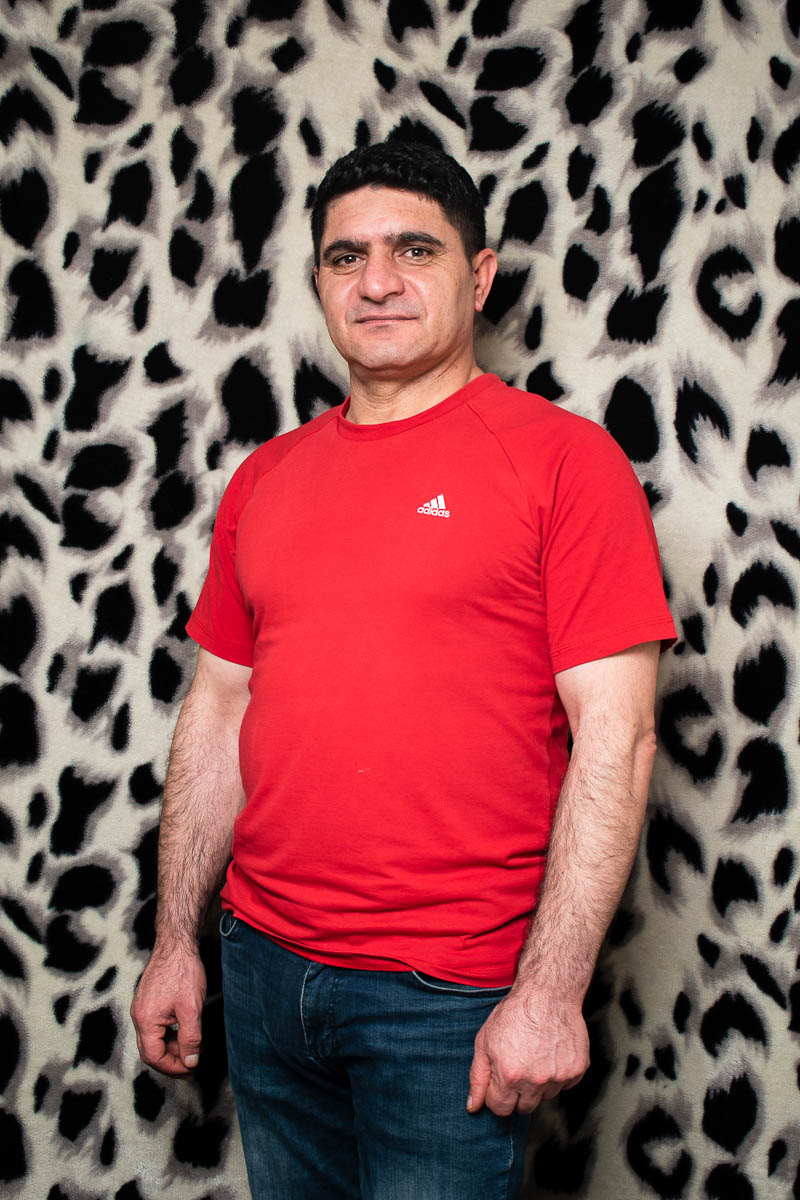 Portrait of refugee Mir standing against a animal print background