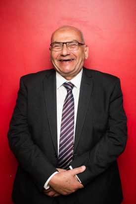 Portrait of refugee Mostafa holding his hands to the front and laughing