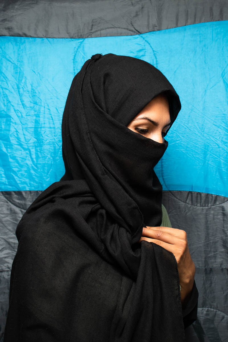 Portrait of refugee Zainab with a black hijab and veil covering lower half her face