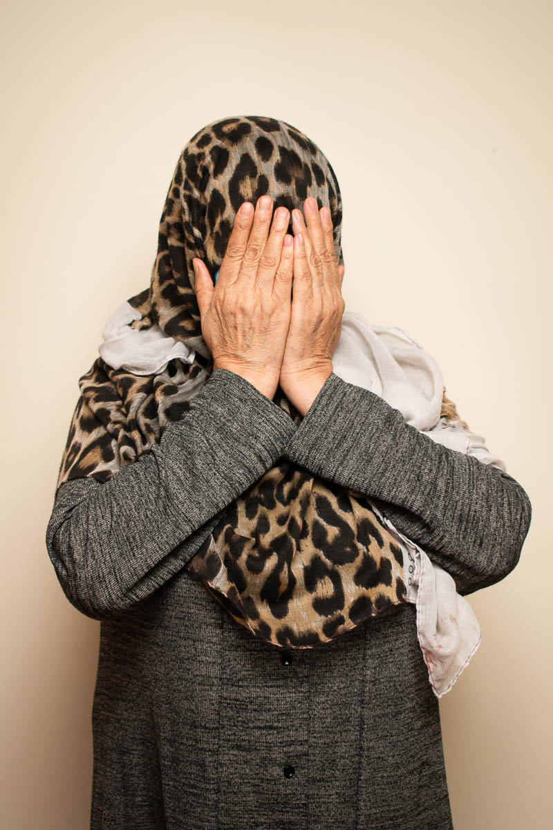 Portrait of refugee Simin hiding her face with her hands
