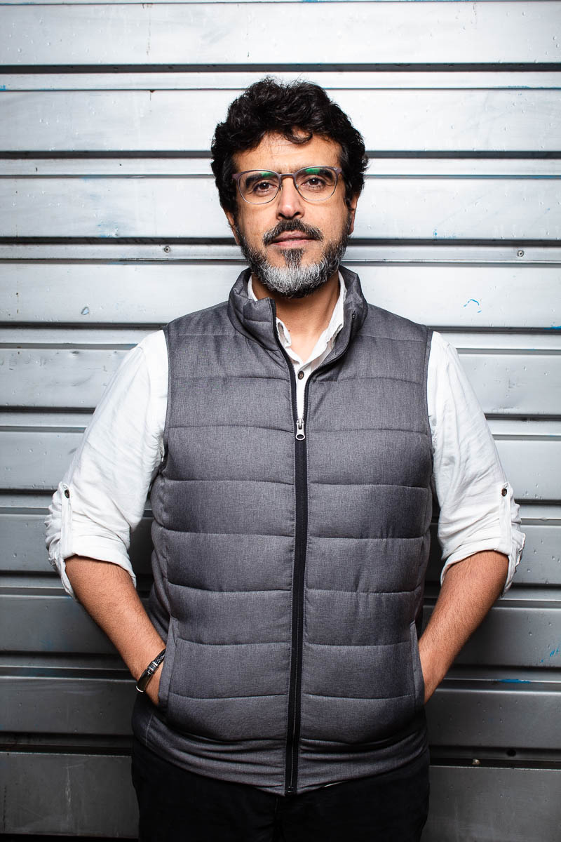 Portrait of refugee Waleed wearing glasses with his hands inside the pockets of his puffer jacket