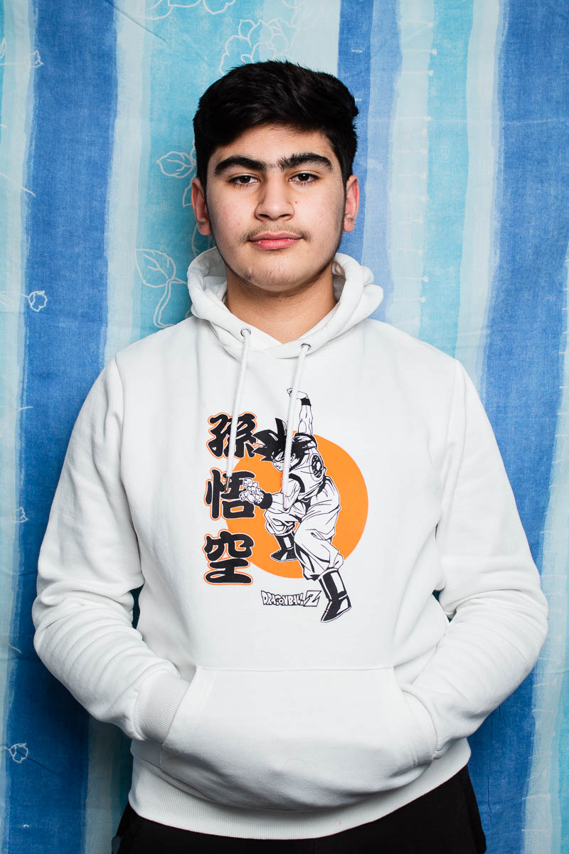 Portrait of refugee Feras with both his hands in the middle pocket of his white hoodie