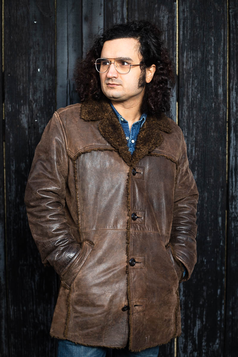Portrait of refugee Hanif in a leather jacket looking sideways