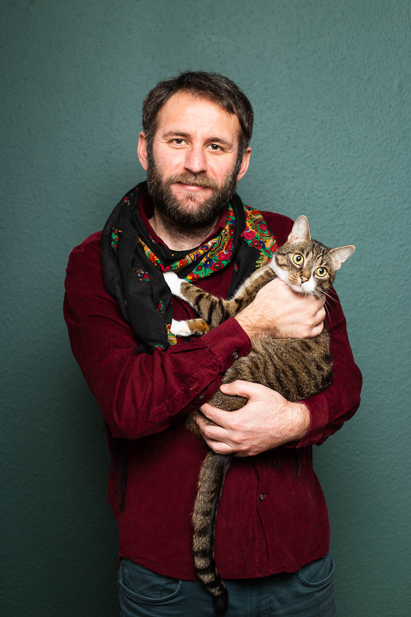 Portrait of refugee Rezan wearing a tradition shawl holding a cat in his arms