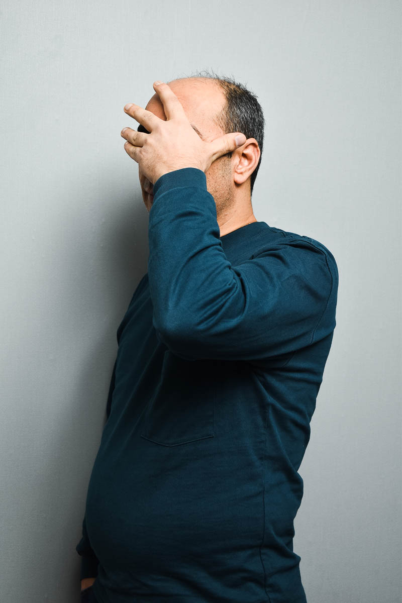 Portrait of refugee Rohjat hiding his face with his left hand