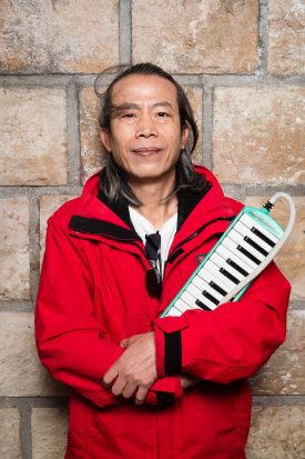 Portrait of refugee Khuntong holding a melodica is his arms