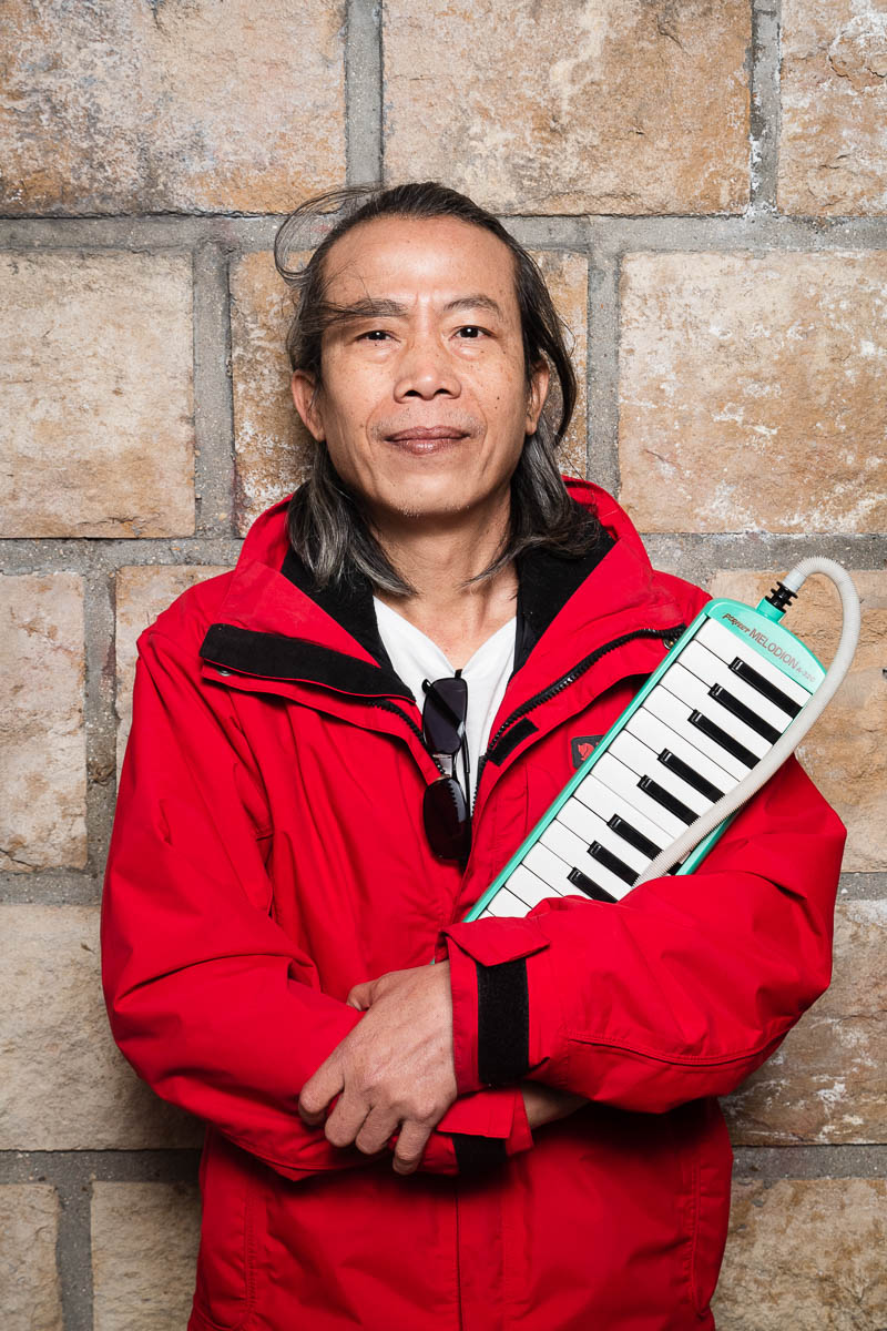 Portrait of refugee Khuntong holding a melodica is his arms