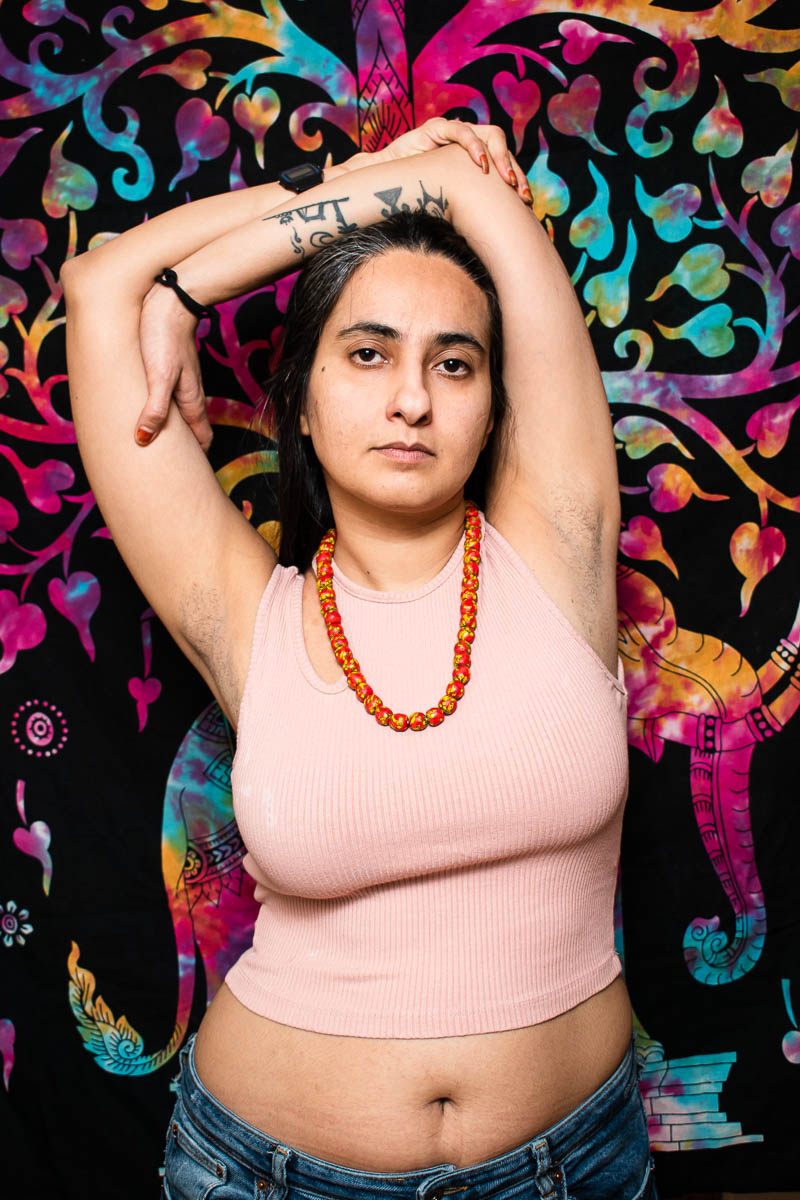 Portrait of refugee Sousan with her tattooed arms folded above her head