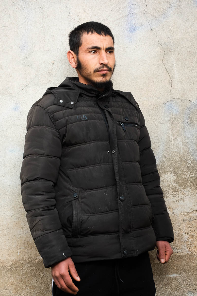 Portrait of refugee Mohamed wearing a puffer jacket and looking to his left