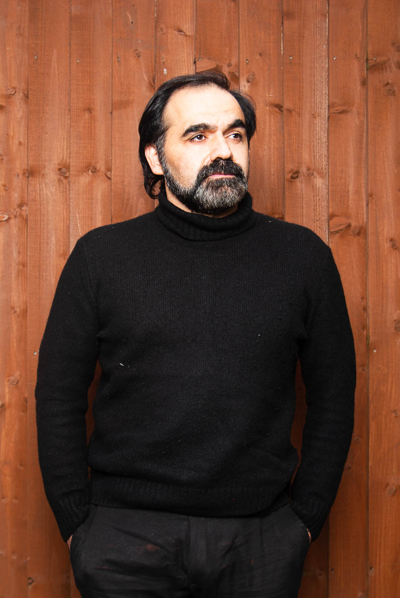 Portrait of refugee Davoud wearing a black turtleneck with his hands in his pockets