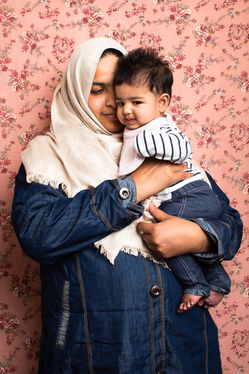 Portrait of refugee Shireen cuddling a baby in her arms