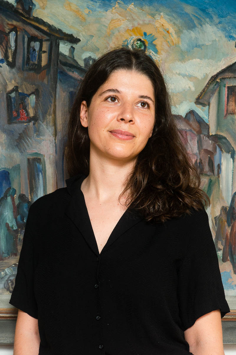 Portrait of refugee Marija standing against a painting
