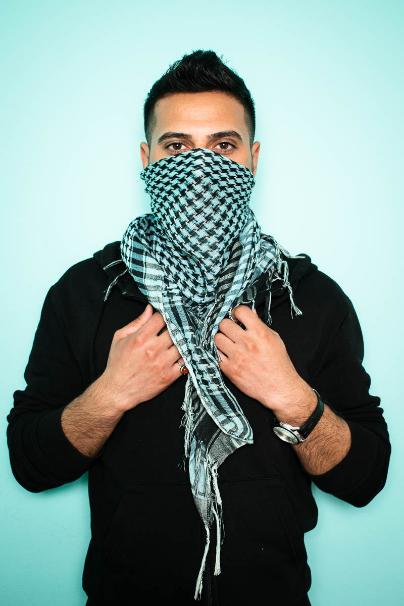 Portrait of refugee Frat with a keffiyeh scarf wrapped around the lower half of his face