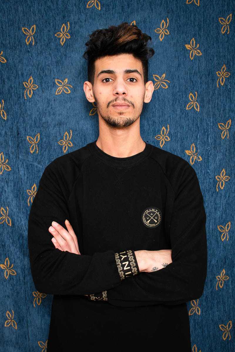 Portrait of refugee Ali standing with his arms crossed