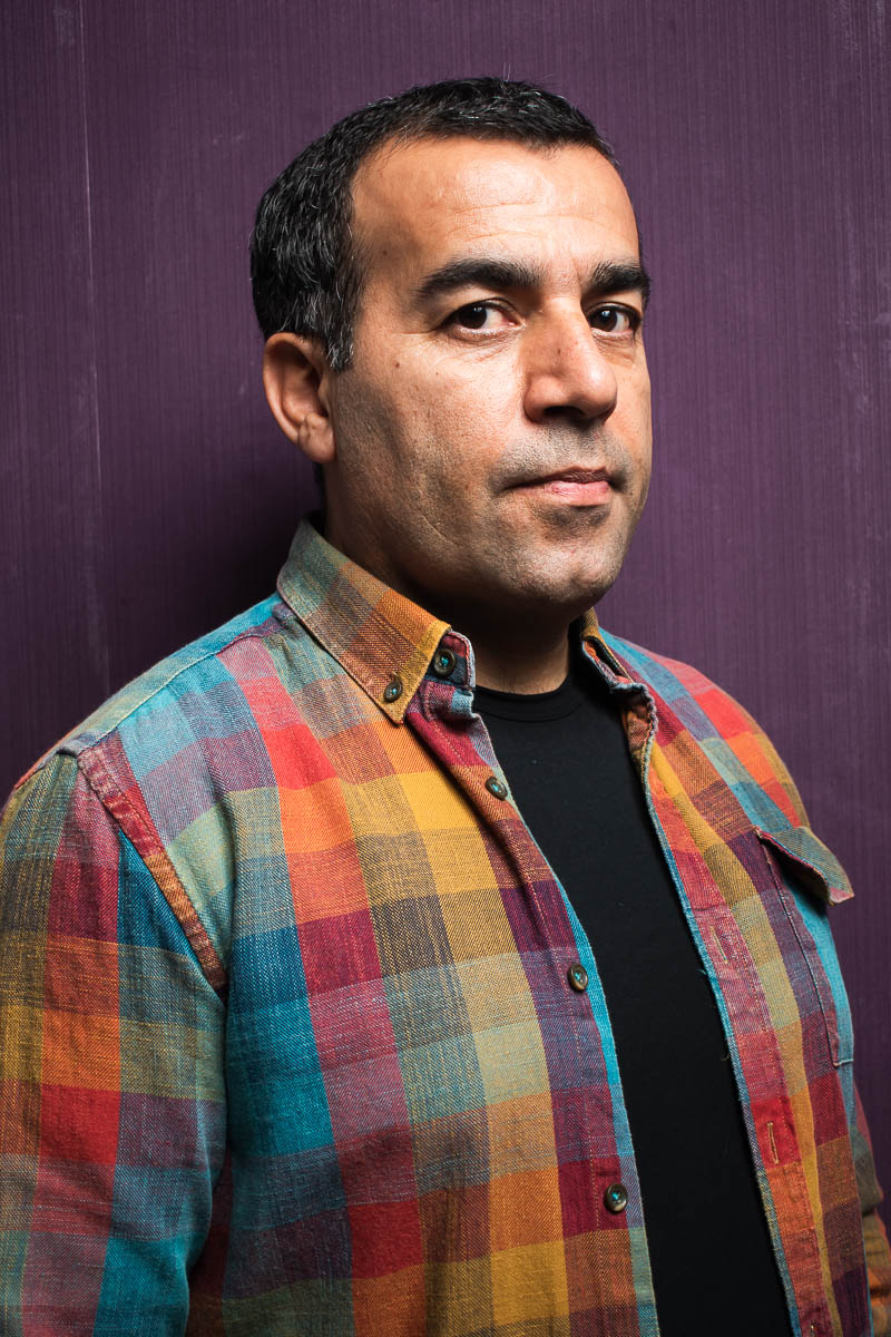 Portrait of refugee Aram wearing a plaid jacket