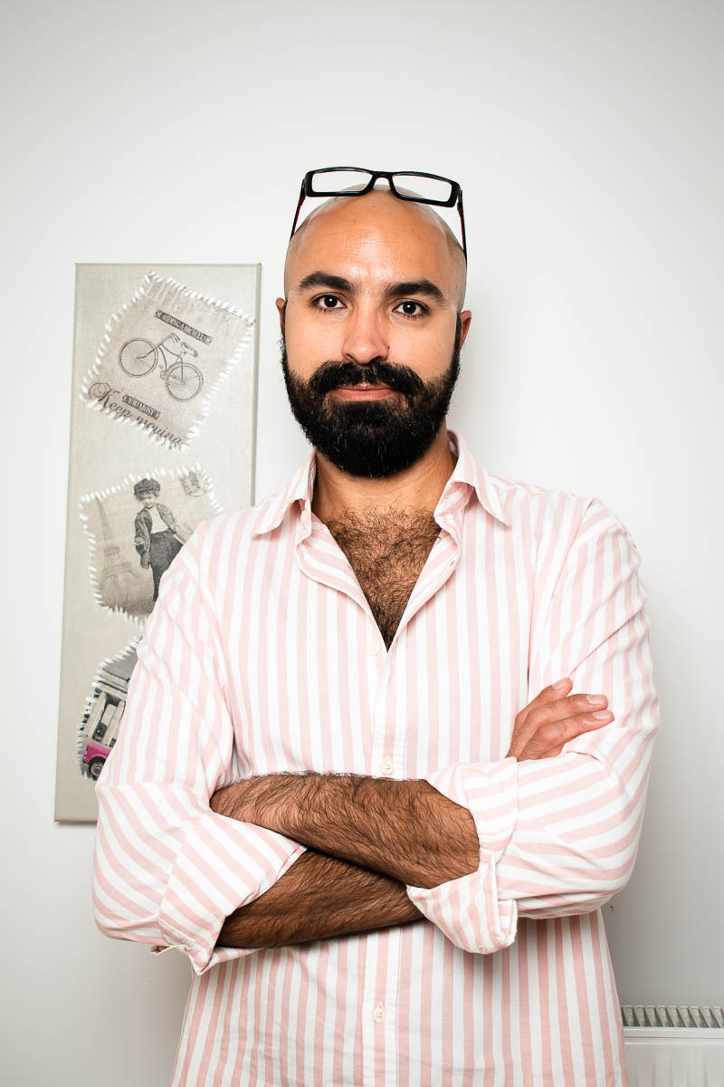 Portrait of refugee Mamadou with his arms crossed and his glasses perched on top of his head