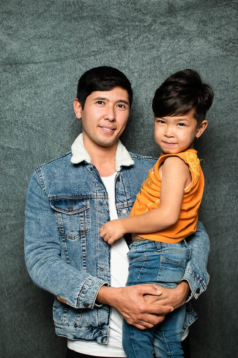 Portrait of refugee Morteza smiling while holding a child in his arms