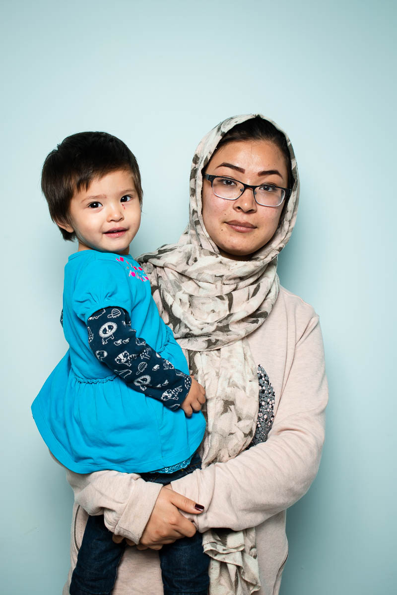 Portrait of refugee Roya with a hijab holding a child in her arms