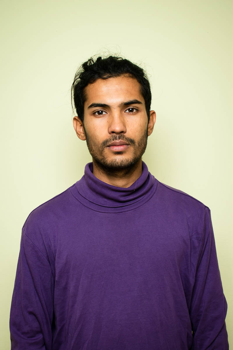 Portrait of refugee Amir wearing a purple turtleneck
