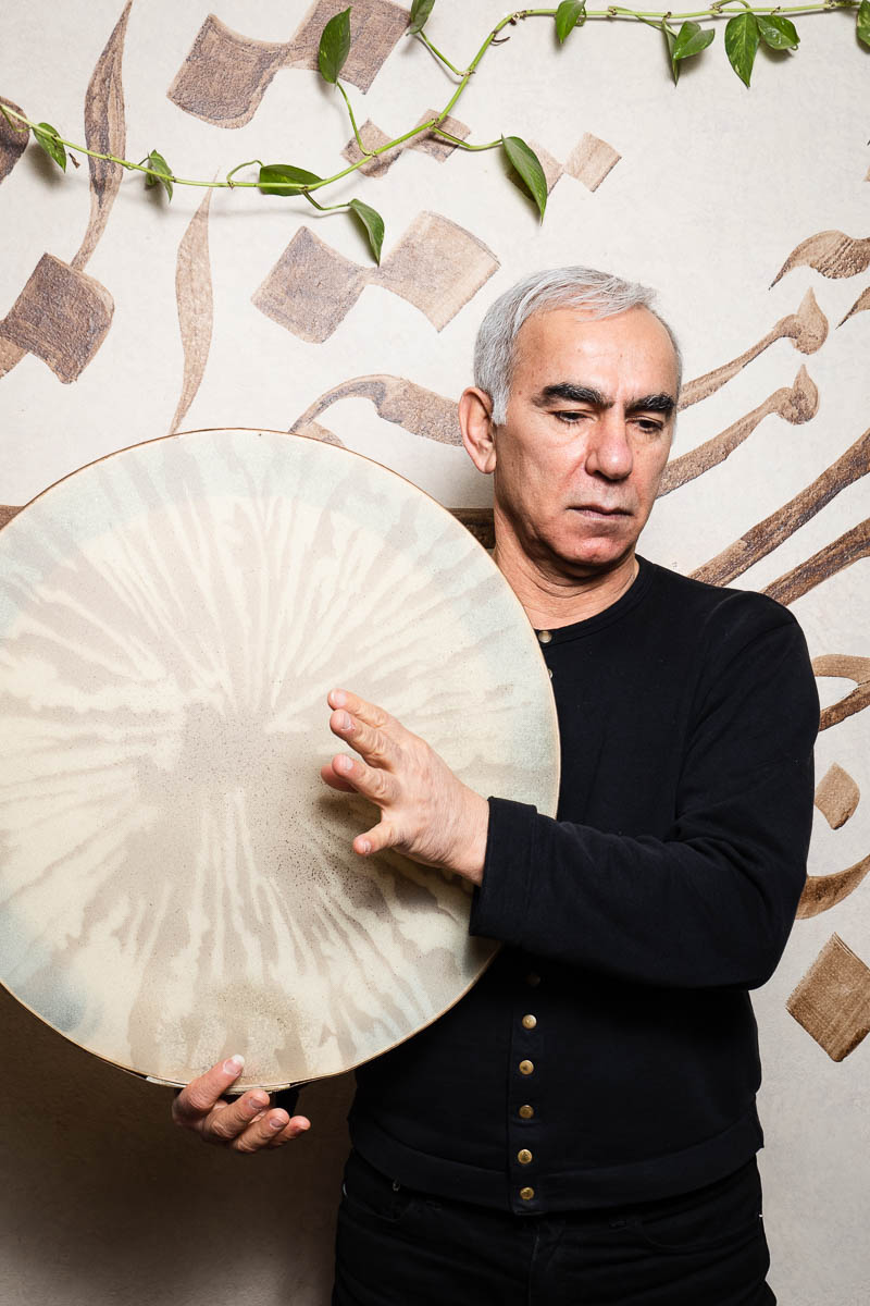 Portrait of refugee Abbas holding a daf (a Persian drum like instrument)