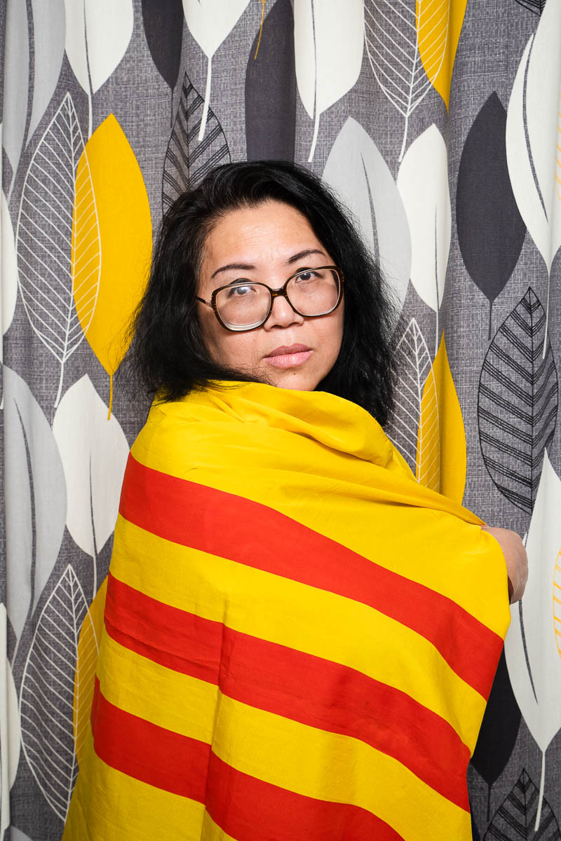 Portrait of refugee Dung-Nghi with the South Vietnam flag wrapped around her