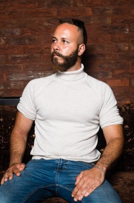 Portrait of refugee Alaa looking to the side sitting with his hands on his legs